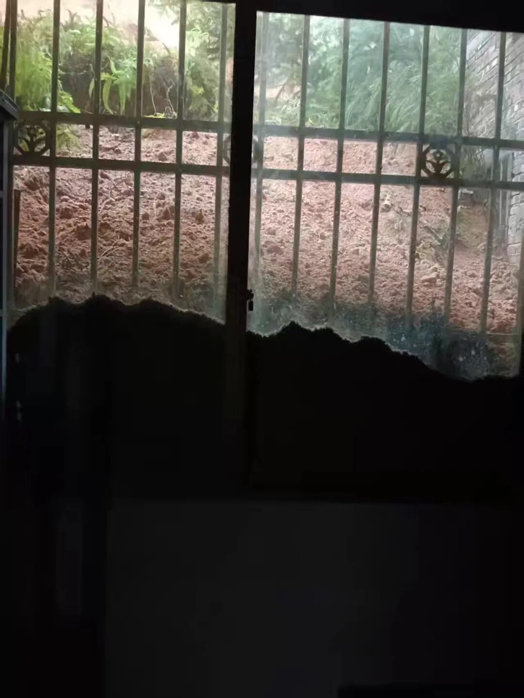 从屋内向外望去,滑坡堆积的泥土已漫过半个窗户的高度 / 受访者供图